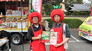 トマトの形の被り物をしたカレーの販売員